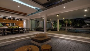 Ett modernt utomhusområde med pool, sittplatser och ett köksutrymme.