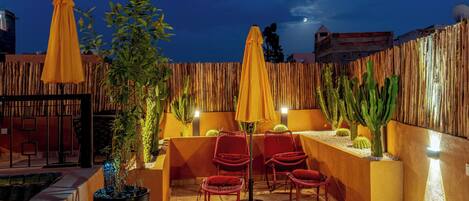 An outdoor patio area with wooden furniture, yellow umbrellas, and cacti.