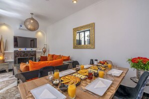 Un coin repas avec une table mise pour le petit-déjeuner, comprenant des assiettes, des verres et une variété d’aliments.