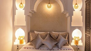 Una camera da letto con un letto, cuscini decorativi e lampade a parete.
