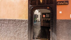 L'ingresso di un hotel con una porta in legno scuro, un'insegna con la scritta "Sahélia" e il numero "29" sopra la porta.