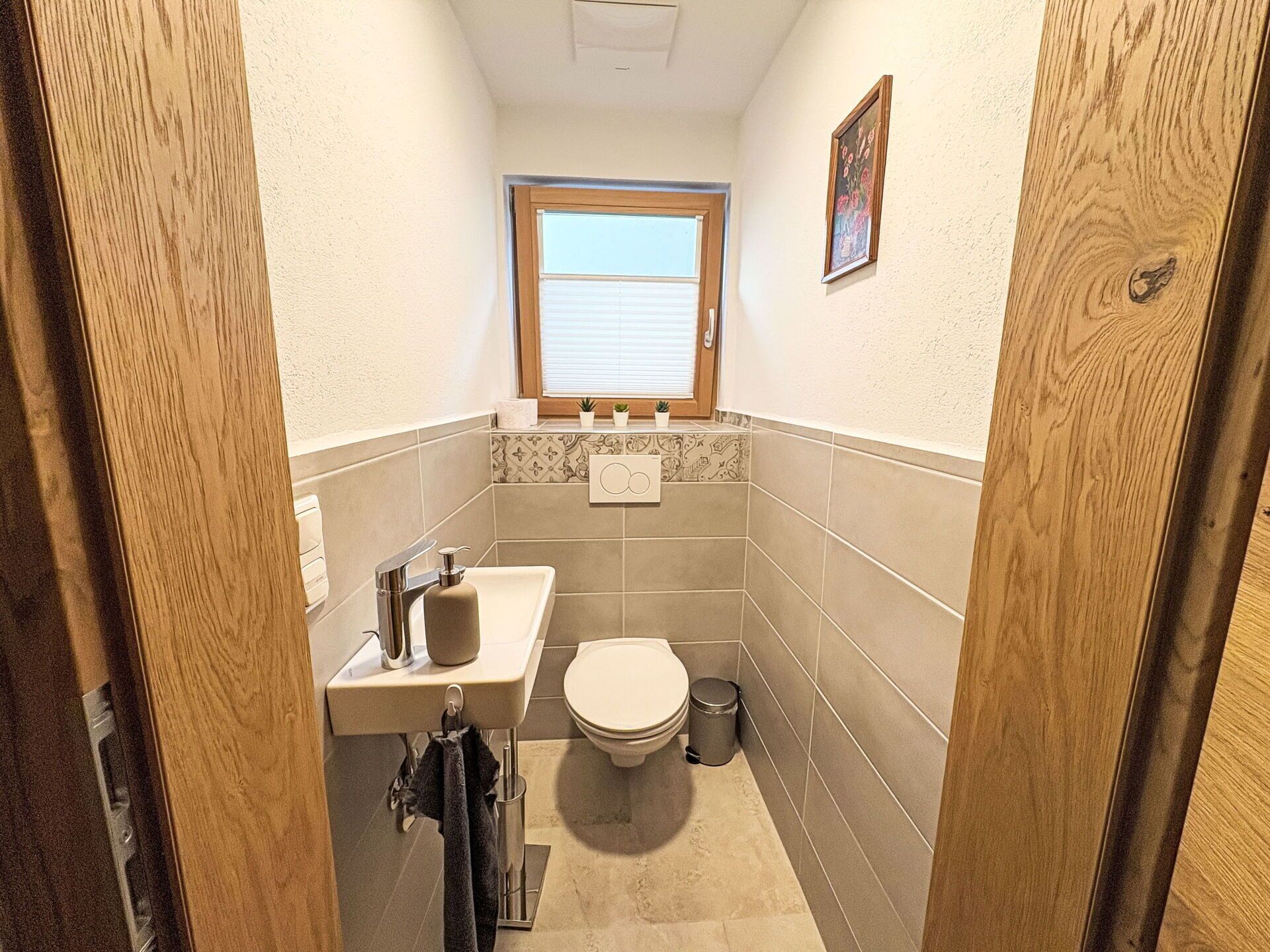A small bathroom with a toilet, sink, and window.