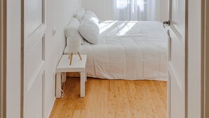 Een slaapkamer met een bed, nachtkastje en een raam met gordijnen.