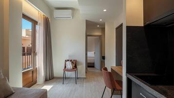 Quarto de hotel moderno com sofá, mesa de jantar, cadeira e cozinha equipada com fogão.