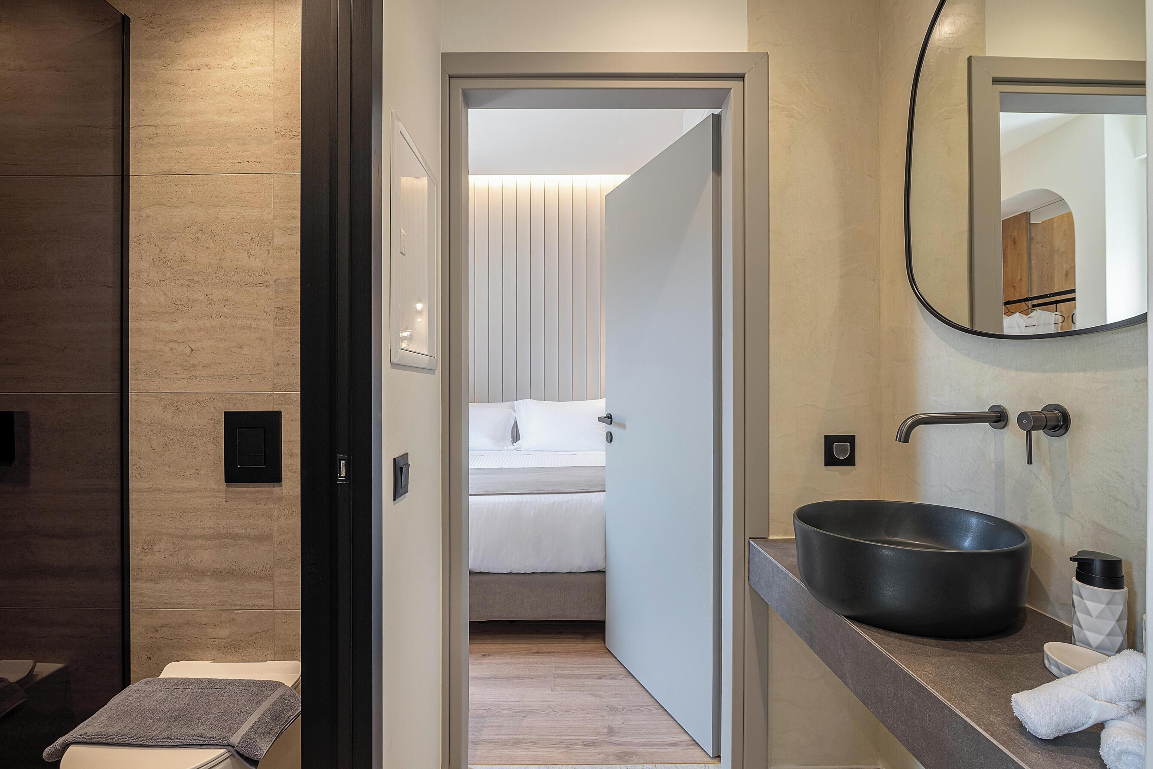 A modern bathroom with a large black sink, a mirror, and a towel rack.