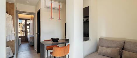 A modern interior with a kitchen area, a dining space, and a seating area with a sofa and a bar stool.