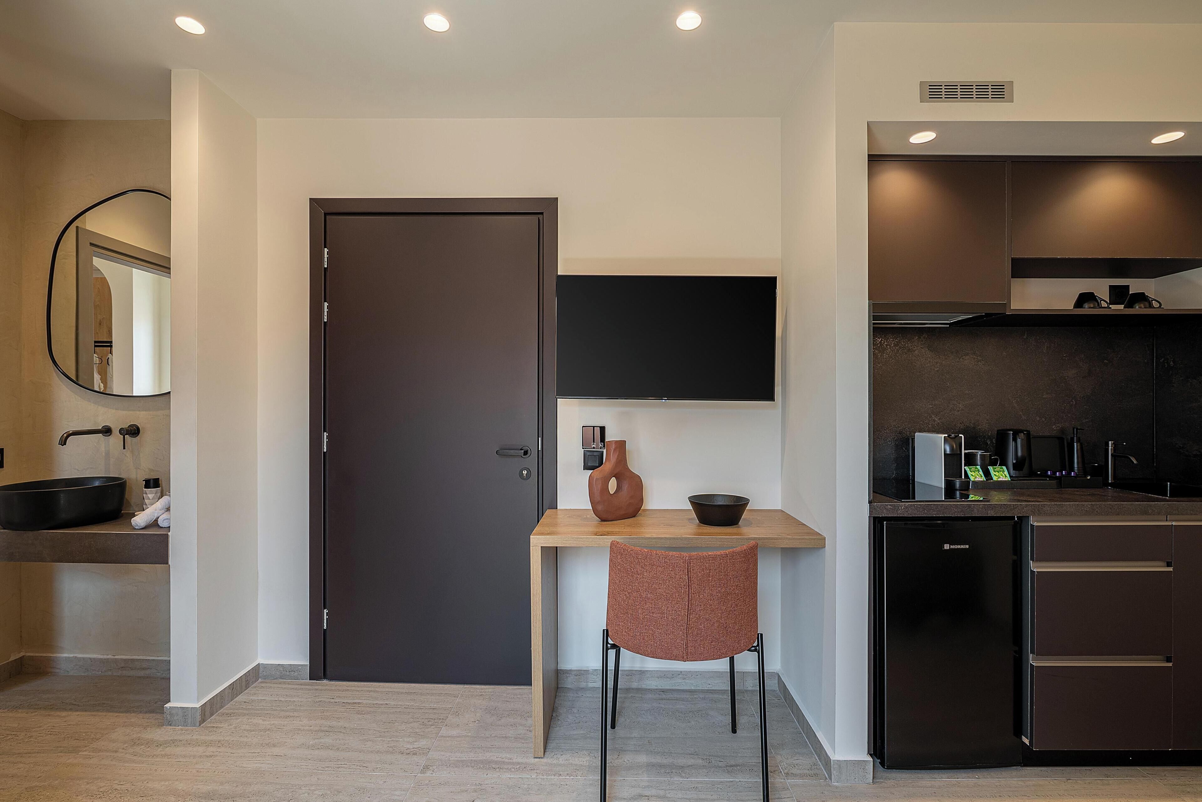 Una cocina moderna con una puerta oscura, una mesa de madera, una silla y un horno empotrado.