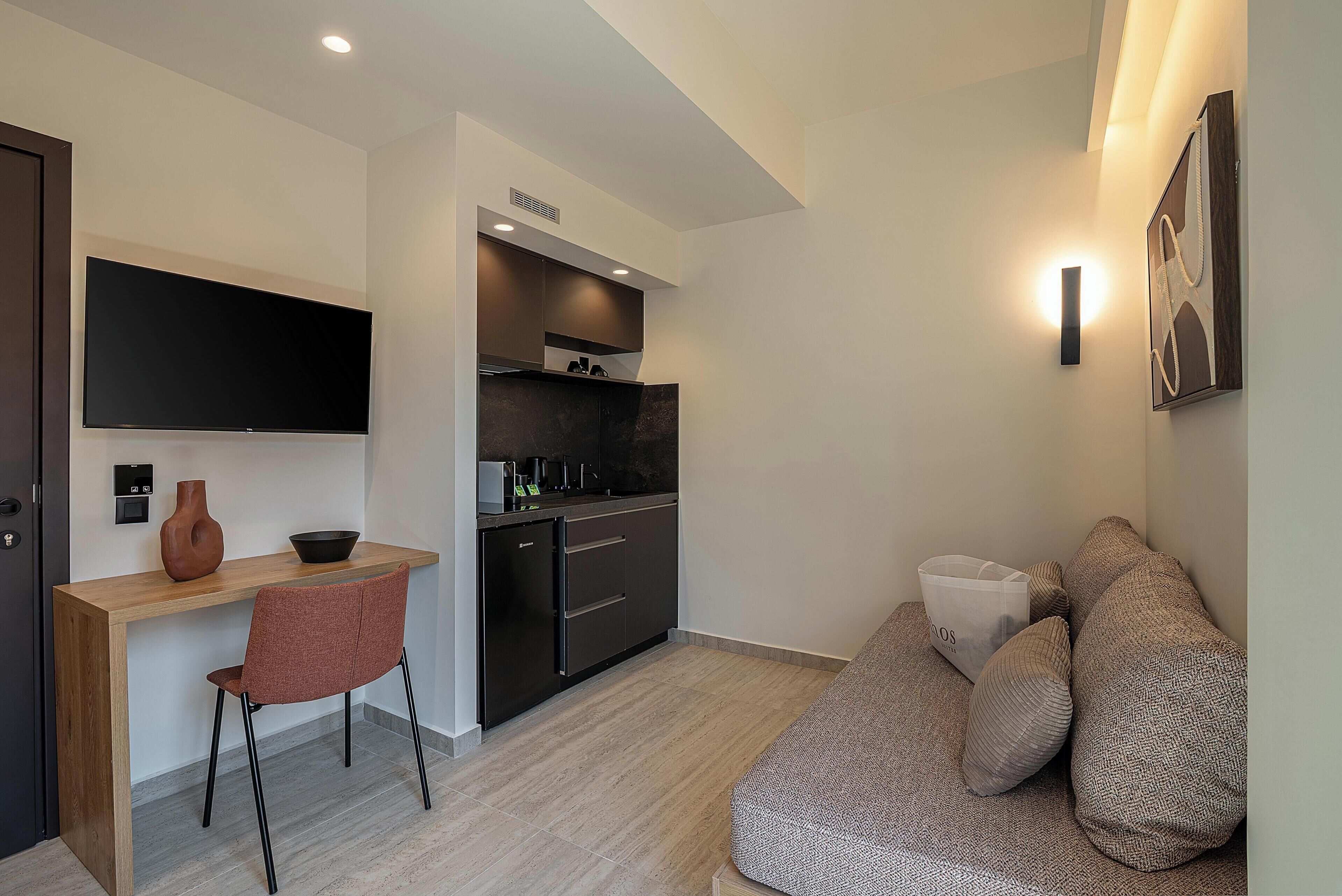 A compact living space with a kitchenette, a dining area, and a seating area with a sofa and cushions.