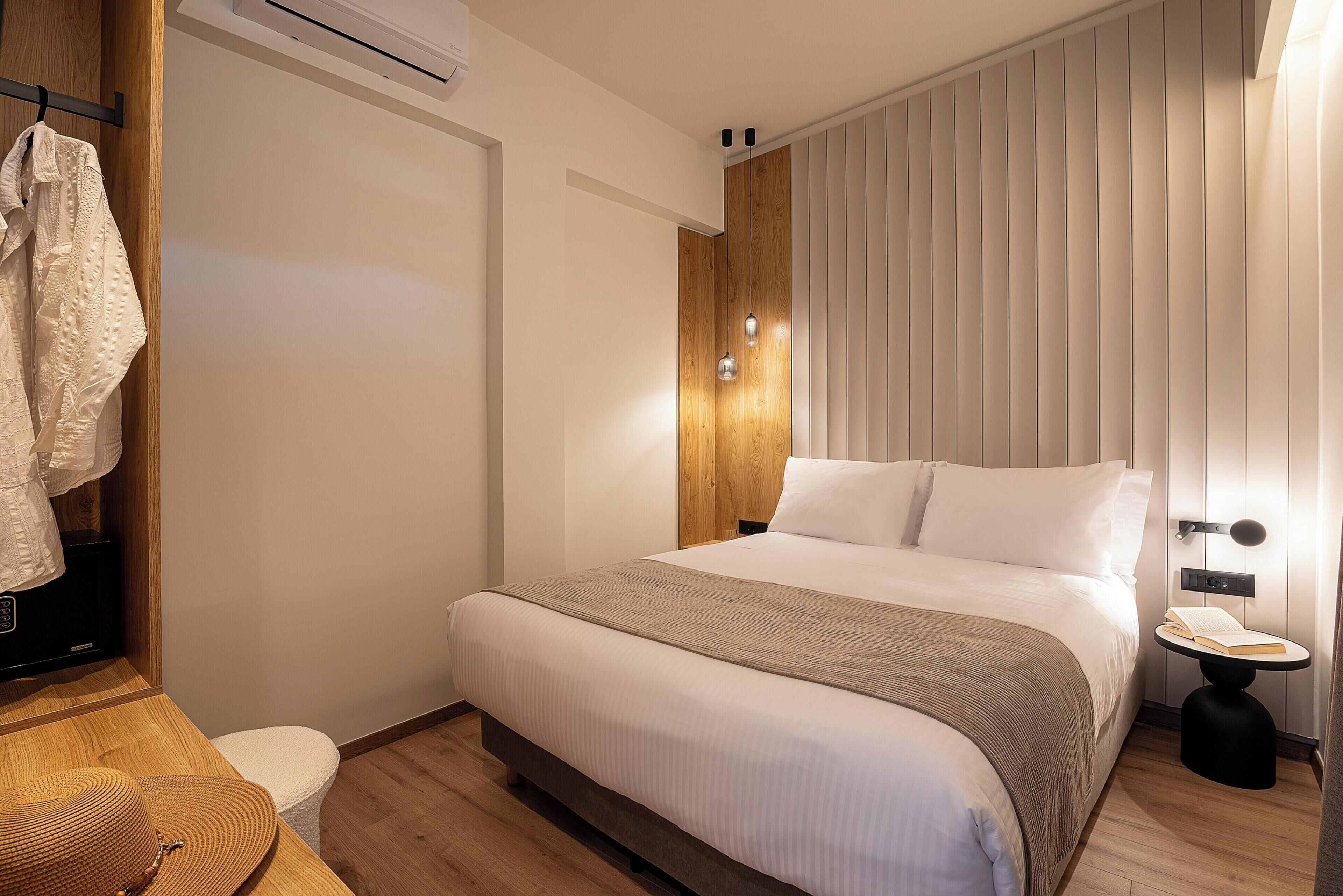 A neatly arranged bedroom with a bed, bedside table, and a small stool.