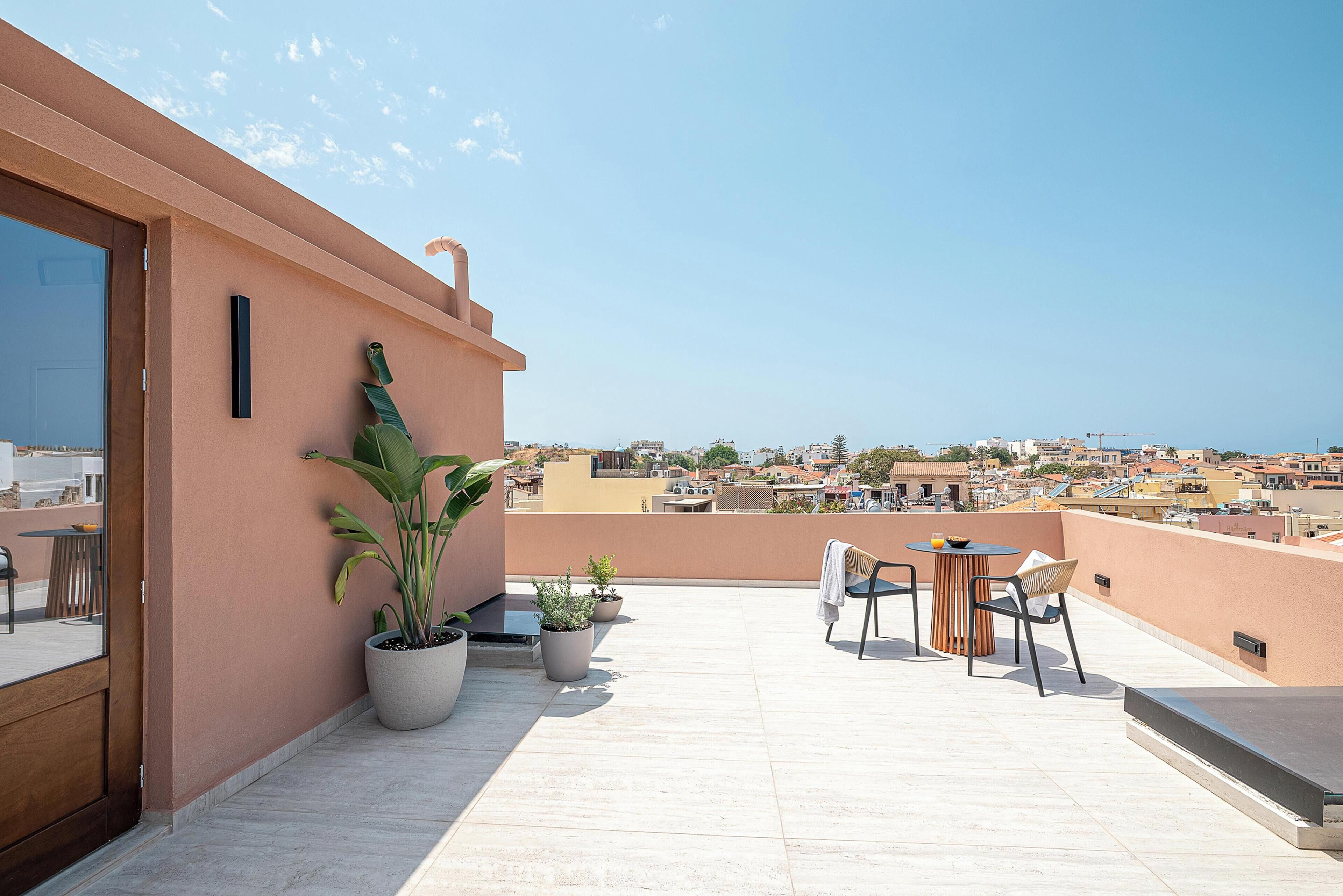Una terraza en la azotea con zona de estar, plantas en macetas y vistas de la ciudad.