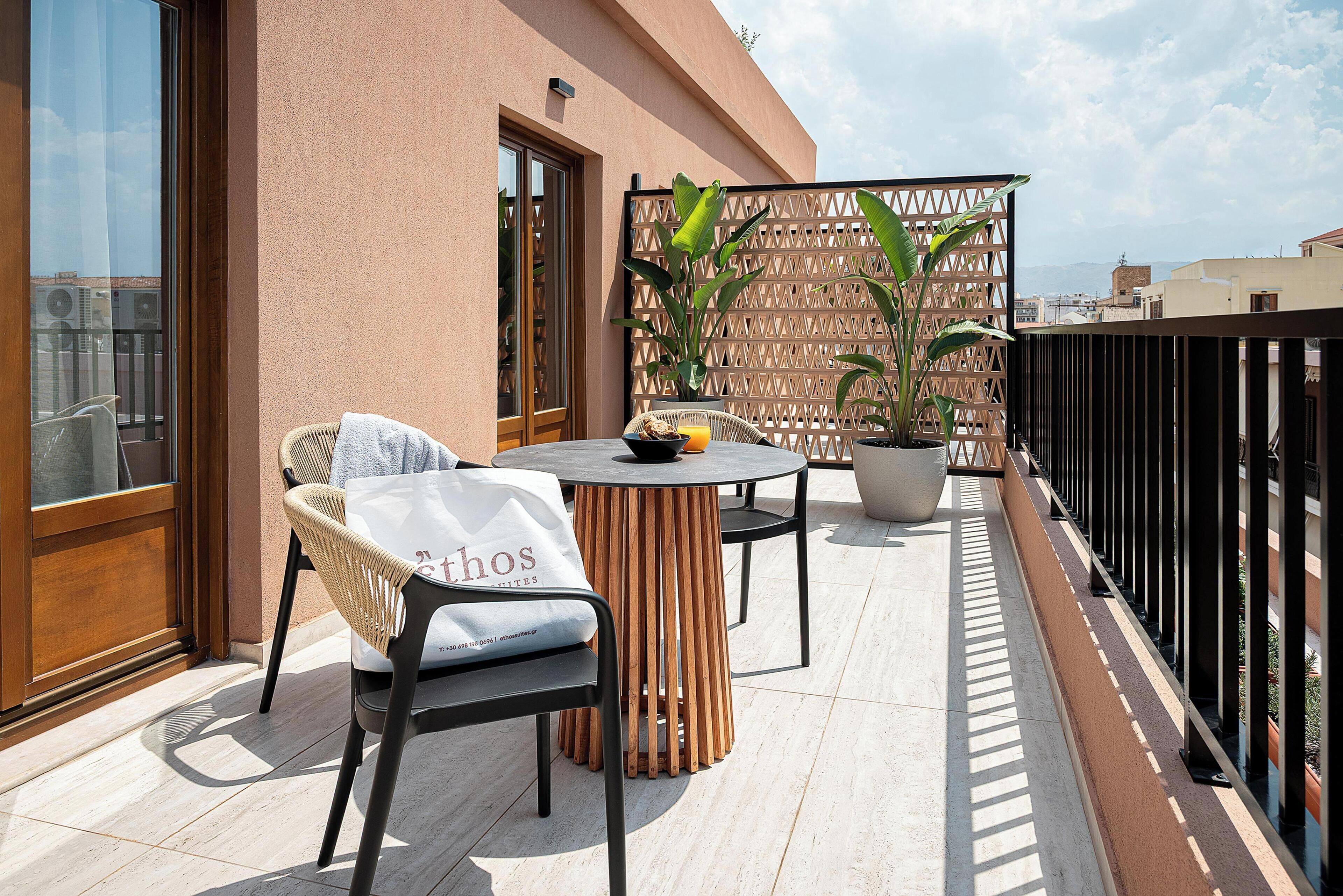 Un balcon avec une table et des chaises, un pot de fleurs et une vue sur le paysage urbain.