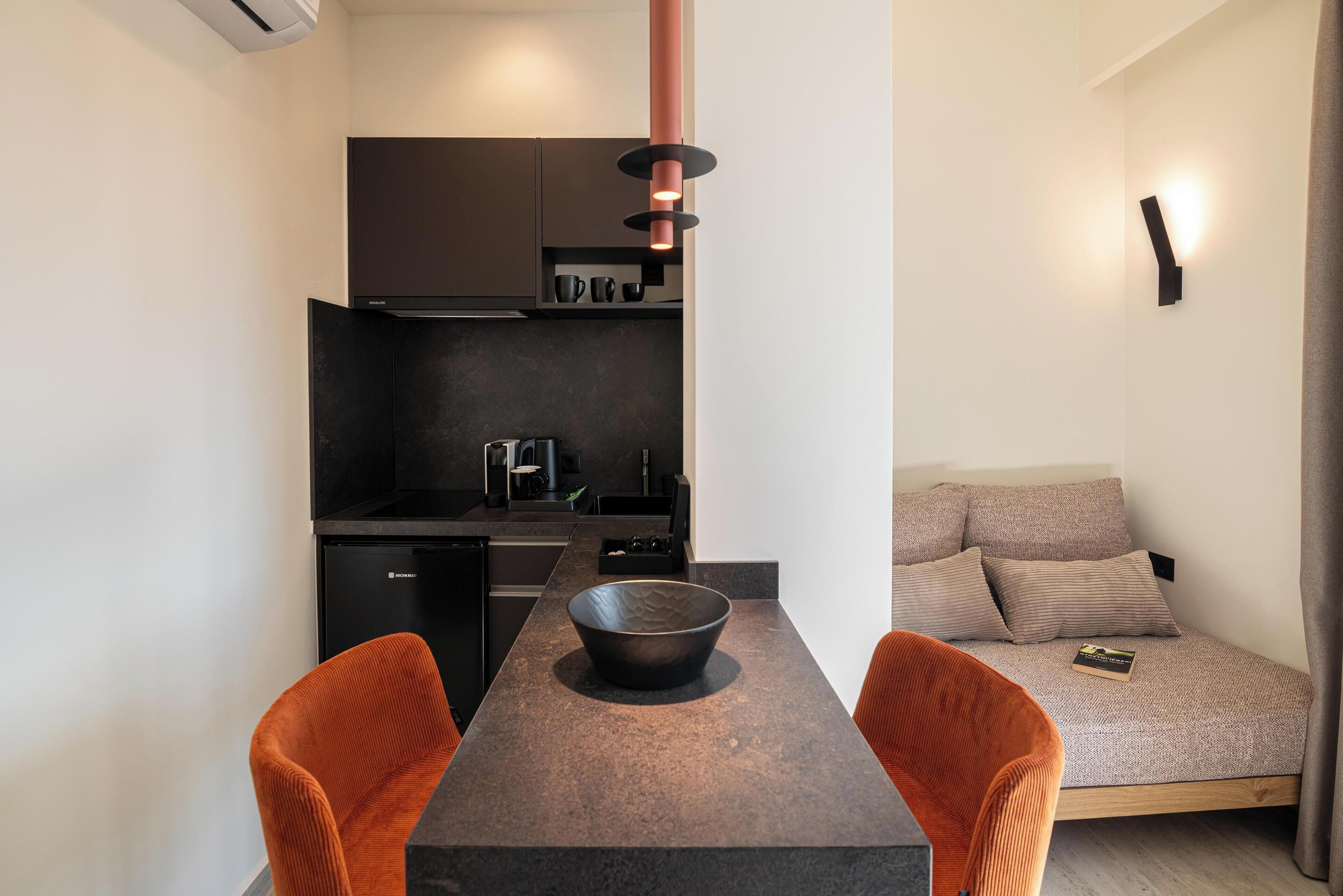 Une cuisine compacte avec une table à manger, deux chaises et un canapé-lit.