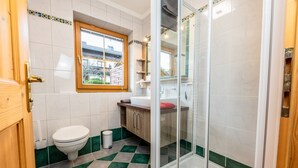 Un baño con inodoro, lavamanos y zona de ducha.