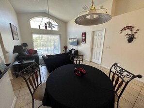 A dining area with a round table, chairs, a ceiling fan, and a window with blinds. - The Beauty of Solana Near Disney and Universal (Davenport)