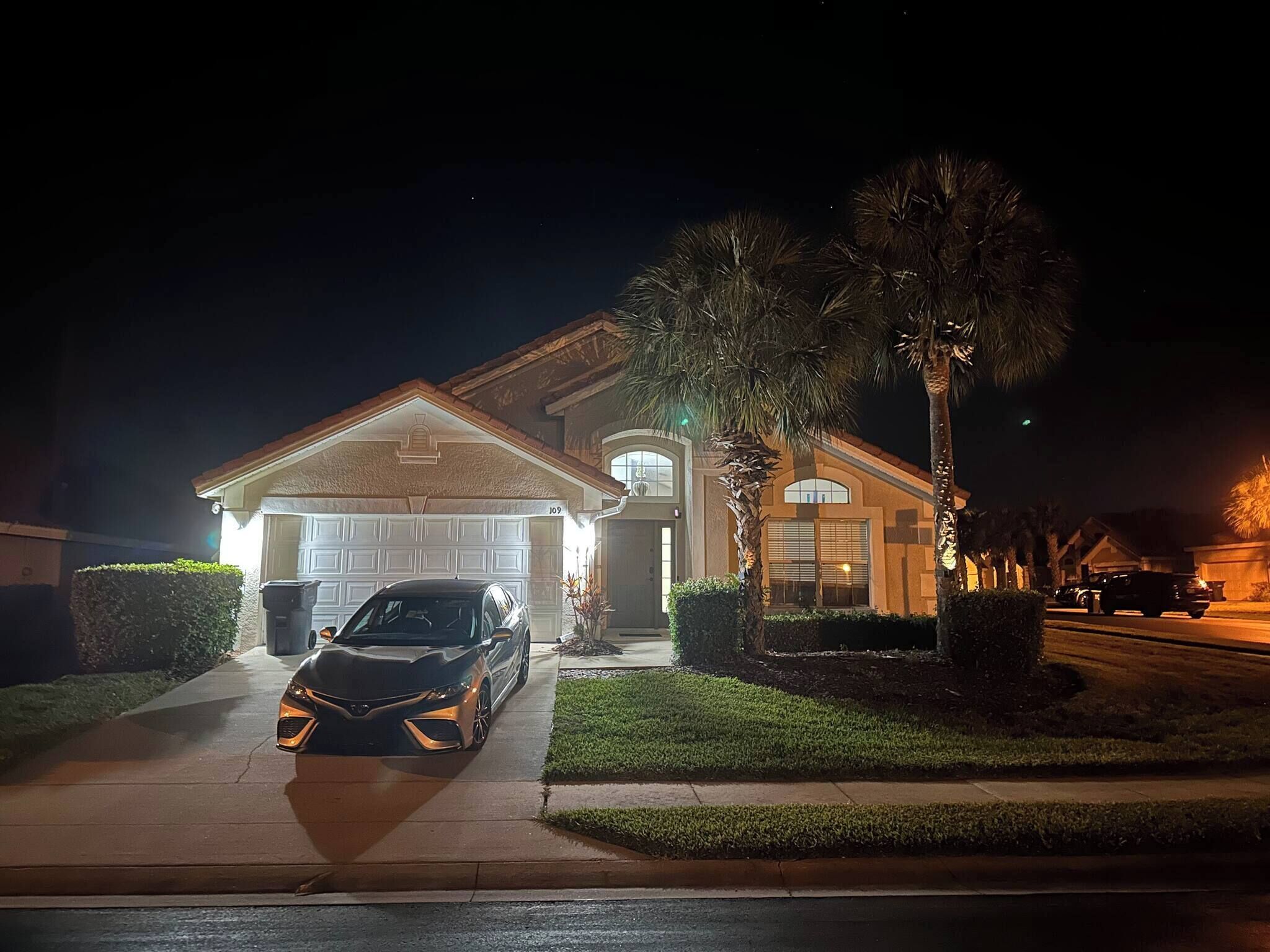 Une maison d’habitation avec un garage, une allée et une voiture garée.