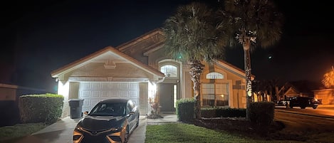 Une maison d’habitation avec un garage, une allée et une voiture garée.