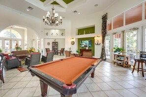 A spacious living room with a pool table, comfortable seating, a television, and a large window with a view. - The Beauty of Solana Near Disney and Universal (Davenport)