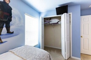 Un dormitorio con cama, armario y ventana.