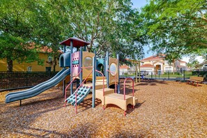 Un parque infantil con tobogán, estructuras para escalar y una zona de juegos techada.