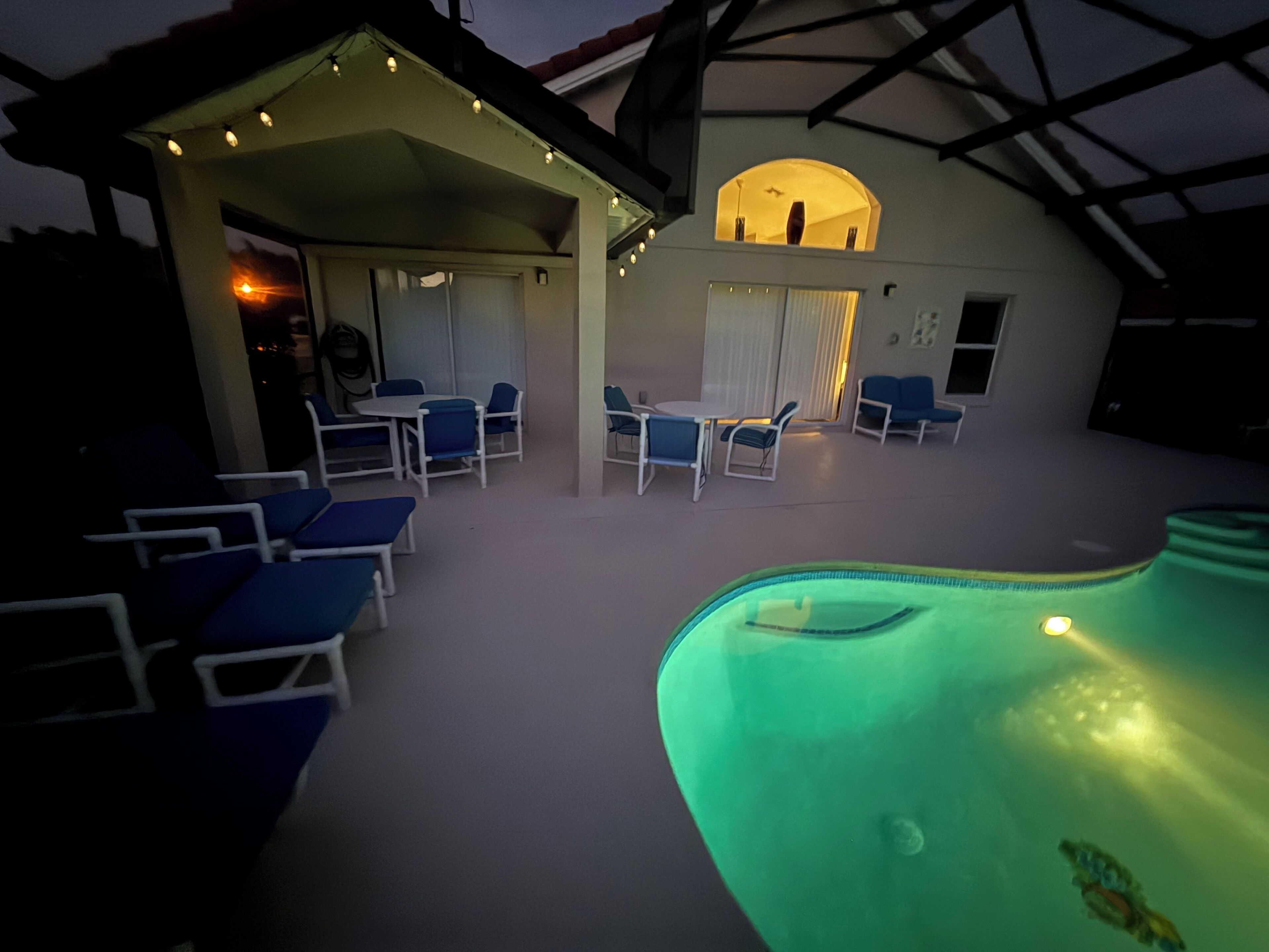 An indoor swimming pool area with lounge chairs and a covered seating area.