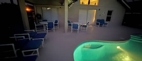 An indoor swimming pool area with lounge chairs and a covered seating area.