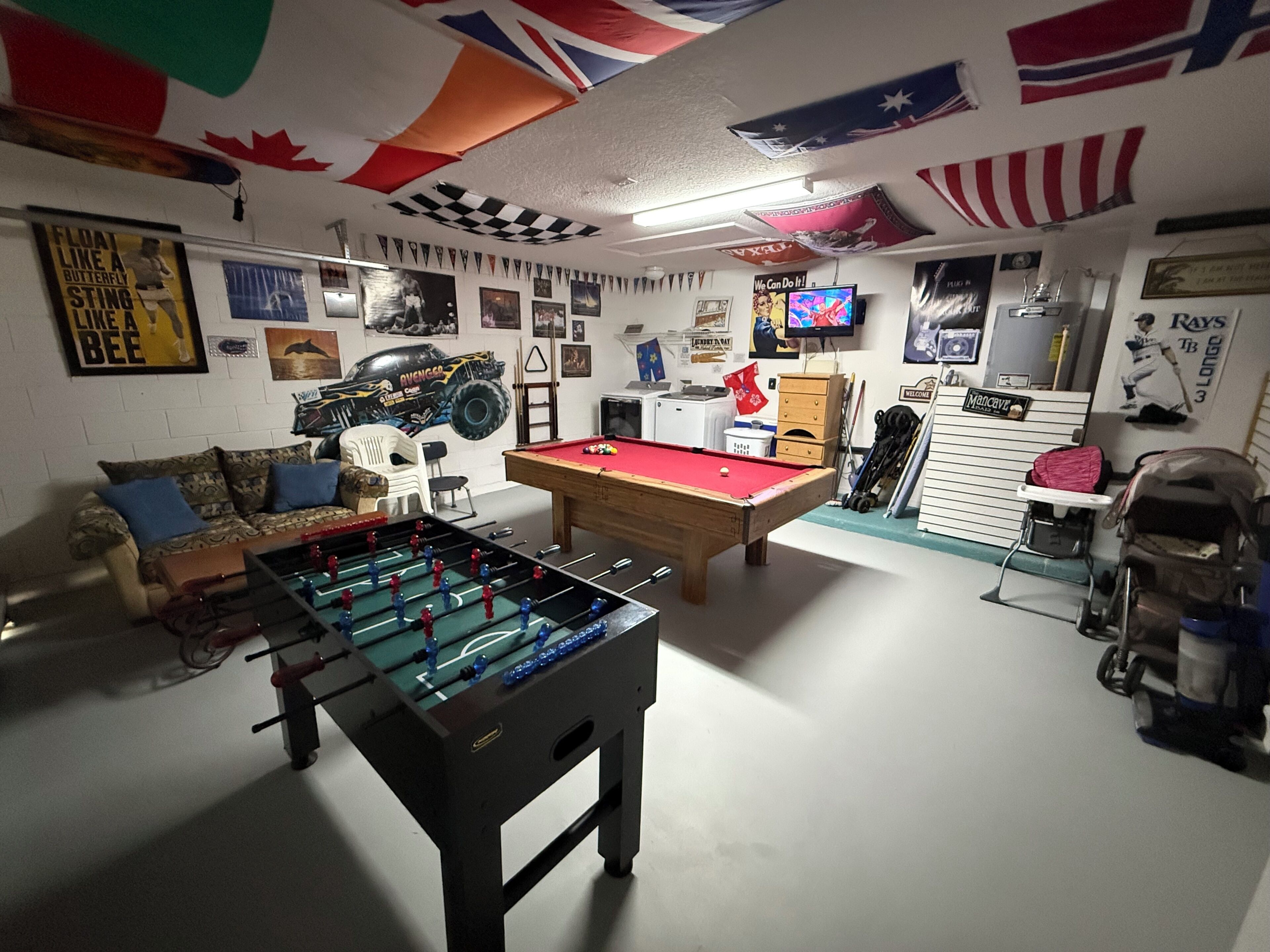 A room with a foosball table, pool table, and various sports memorabilia.