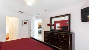 A bedroom with a large bed, a dresser, a mirror, and a TV on the wall. - The Beauty of Solana Near Disney and Universal (Davenport)