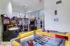 Una habitación con varios juegos de arcade, incluyendo 'Golden Tee' y 'Hot Stuff', y una mesa de shuffleboard.