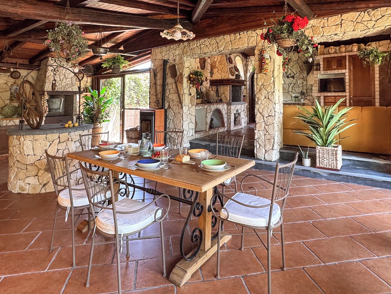 A rustic stone fireplace, a wooden dining table with chairs, and a stone wall.