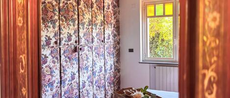 A room with a floral-patterned sliding door, a wooden table with a tray of items, and a window with a view of greenery.