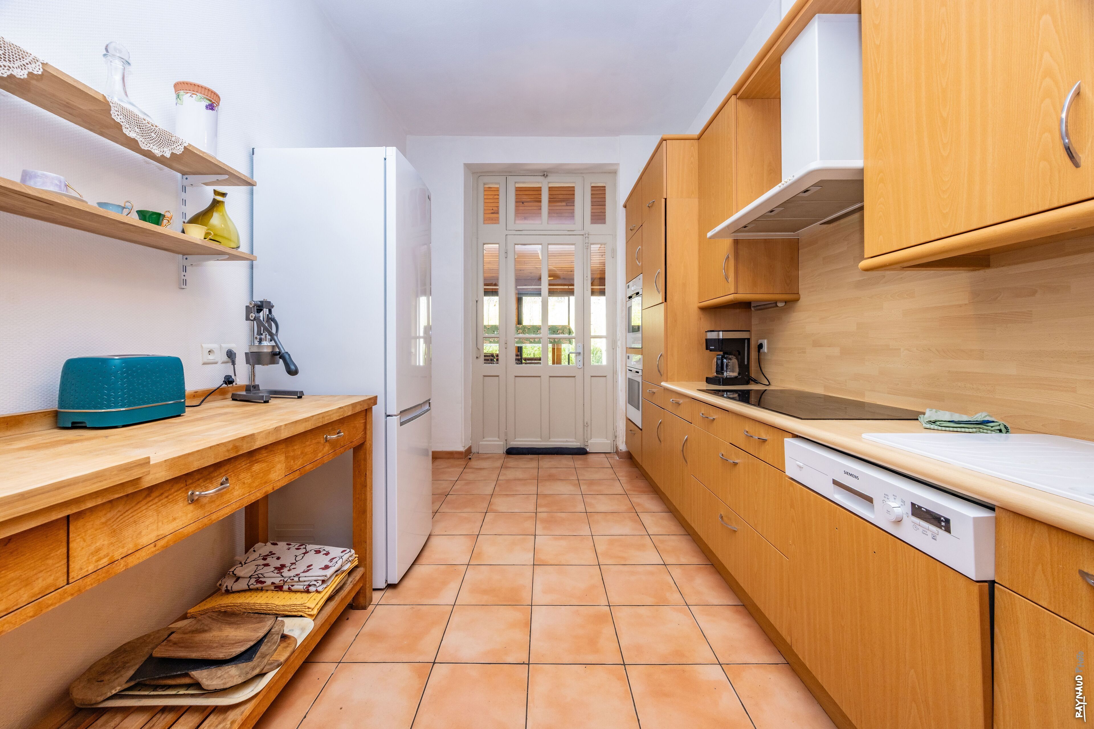 Una cocina compacta con armarios de madera, un refrigerador blanco y un lavavajillas Siemens.