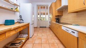 A compact kitchen with wooden cabinets, a white refrigerator, and a tiled floor.