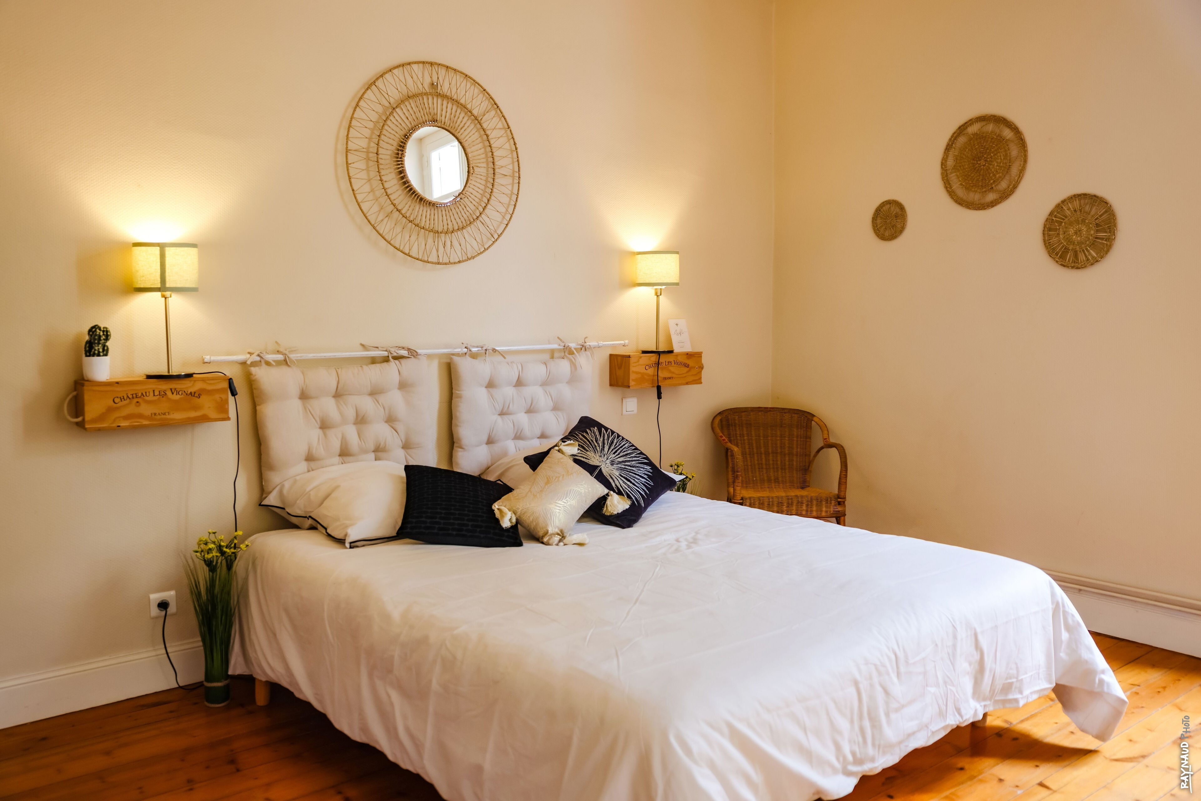 Een slaapkamer met een groot bed, twee bedlampen, een spiegel en decoratieve wandplaten.