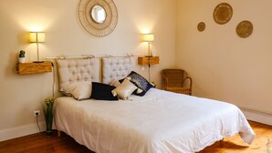 A bedroom with a large bed, two bedside lamps, a mirror, and decorative wall plates.