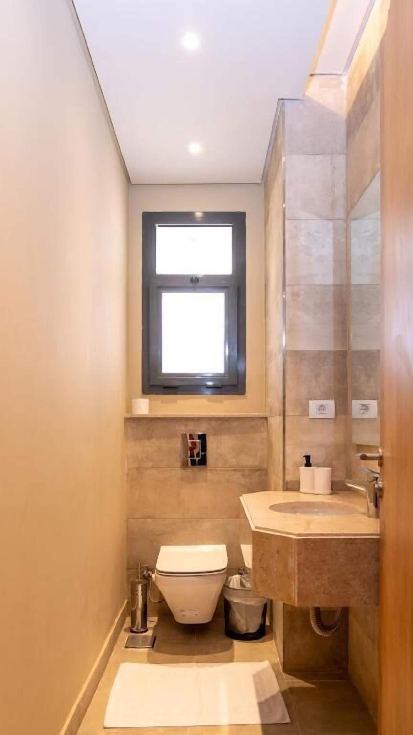 Un baño pequeño con inodoro, lavamanos y ventana.