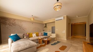 A modern living room with a sofa, coffee table, and a rug. There is a kitchen area in the background. - Kennah Studio | Villette Sodic, New Cairo (New Cairo)