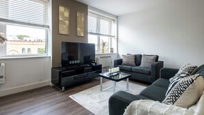 Una sala de estar moderna con una televisión de pantalla plana, un sofá y una mesa de centro.
