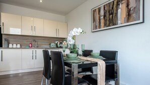 Una cocina moderna con armarios blancos, una mesa de comedor con platos verdes y un florero con flores blancas.