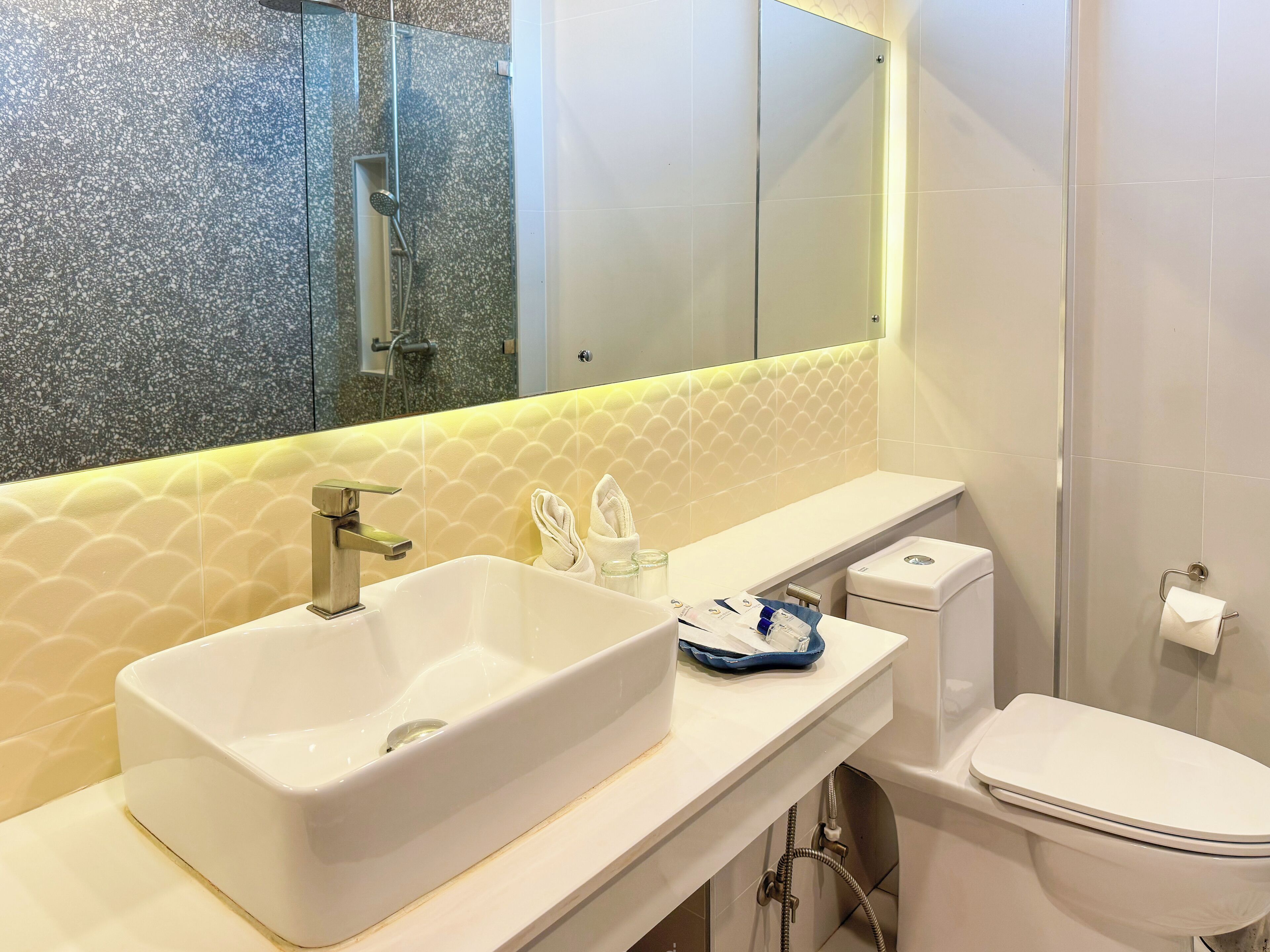 A bathroom with a white sink, a mirror, a toilet, and a shower.