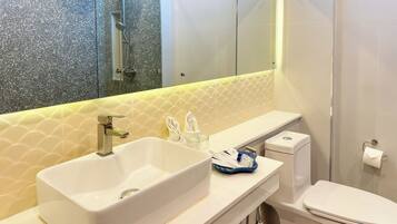 A bathroom with a white sink, a mirror, a toilet, and a shower.