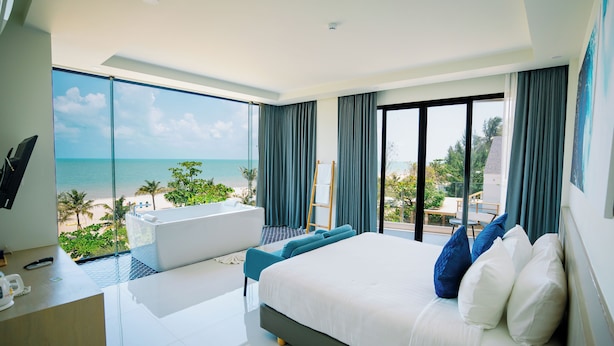 A modern hotel room with a large bed, a balcony with a view of the beach, and a pool area. - Seava Beach (Tha Sala)