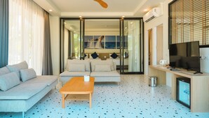 A modern living room with a sofa, a coffee table, a TV, and a ceiling fan. - Seava Beach (Tha Sala)