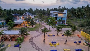 A resort with a beach area, palm trees, and a dining area with umbrellas. - Seava Beach (Tha Sala)