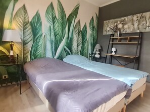 Ein Schlafzimmer mit Bett, Nachttisch, Lampe, Wandbild und Regal.
