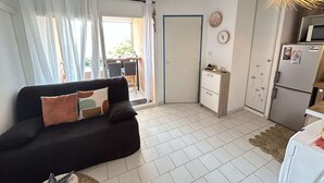 A compact living space with a sofa, a small kitchenette, and a dining area.