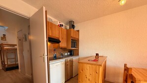 Una cocina compacta con armarios de madera, un microondas integrado y una pequeña mesa de madera.