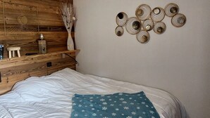 A bedroom with a wooden headboard, a bed with white bedding and a blue pillow, and wall decor including a sunburst design and circular patterns.