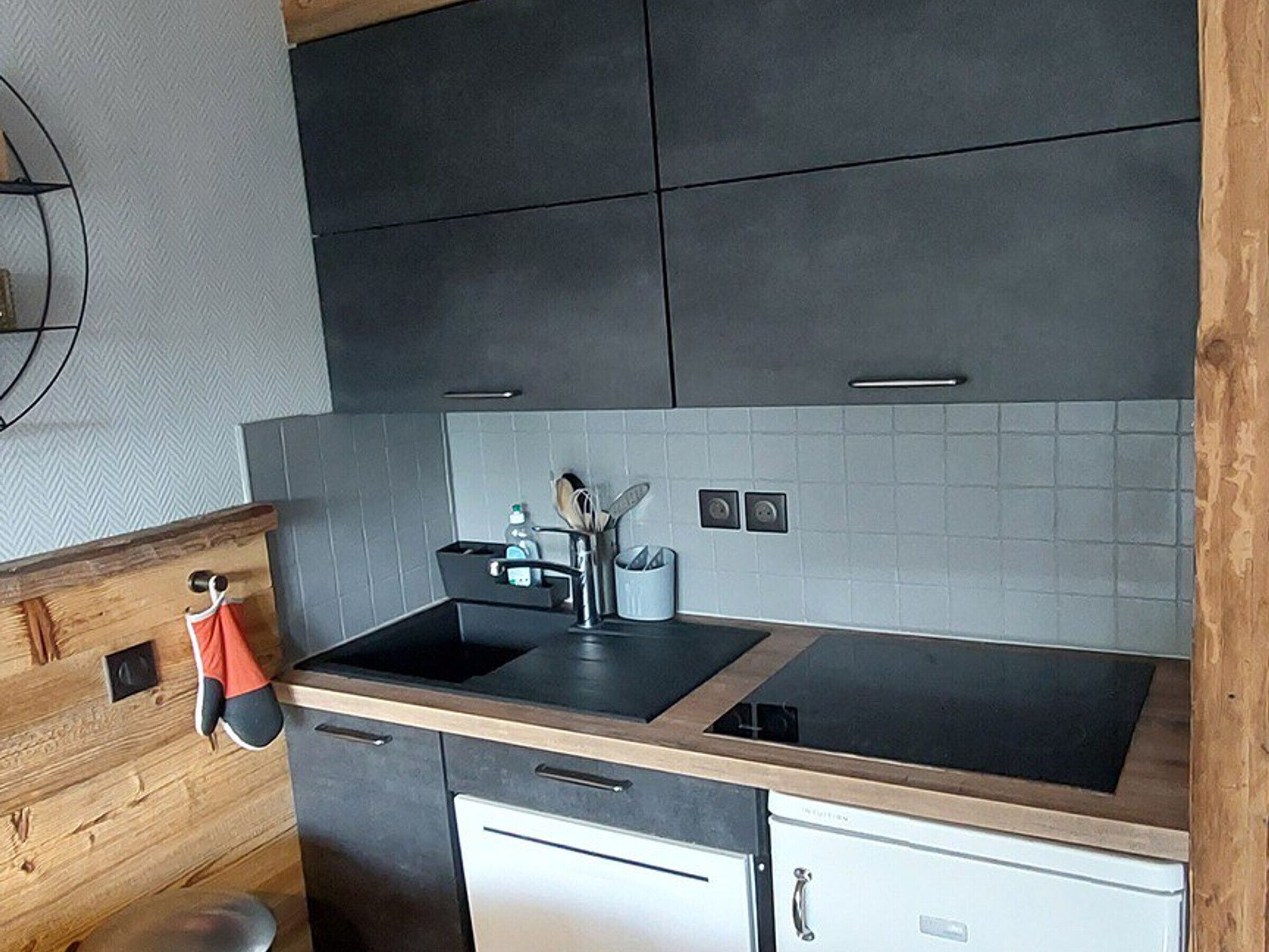 Una cocina moderna con armarios oscuros, una encimera negra y una estufa integrada.