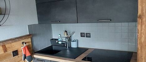 Una cocina moderna con armarios oscuros, una encimera negra y una estufa integrada.