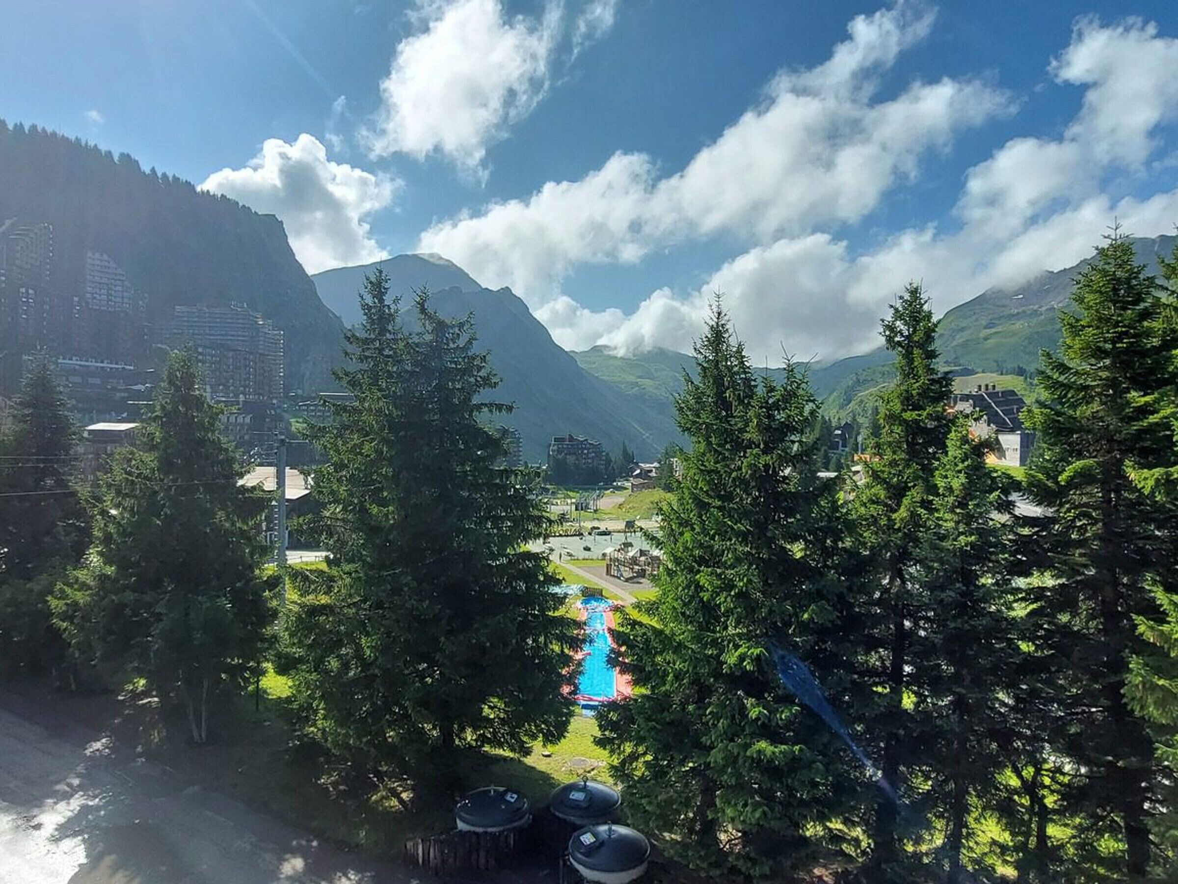 Un paysage montagneux avec un ciel dégagé, une piscine et des bâtiments en arrière-plan.